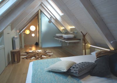 Suite bajo cubierta, techo madera blanca, dormitorio con baño: Reforma y decoración de vivienda en Baqueira (Valle de Arán-Pirineos)